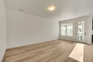 Spare room with light hardwood / wood-style floors and an inviting chandelier