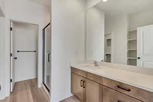 Bathroom with hardwood / wood-style floors, vanity, and an enclosed shower