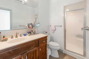 Basement Bathroom with tile patterned flooring, vanity, toilet, and a shower with door