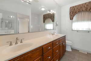 Bathroom featuring tile patterned flooring, vanity, toilet, and a shower with door