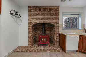 Interior space with light tile patterned floors, visible vents, a wood stove, and a sink
