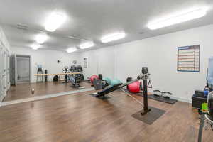 Exercise area with a textured ceiling and dark hardwood / wood-style flooring