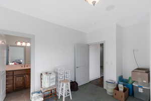 Carpeted bedroom featuring ensuite bath and sink