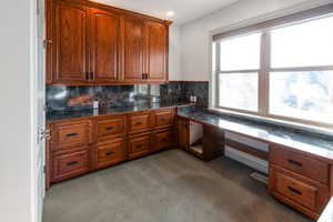 Kitchen featuring carpet, built in desk, and tasteful backsplash