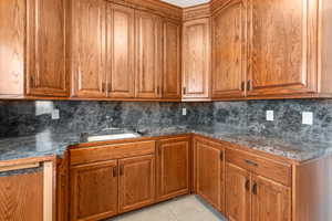 Kitchen featuring decorative backsplash, light tile patterned floors, and sink