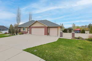 Single story home featuring brick siding, fence, a garage, a front yard, and concrete driveway