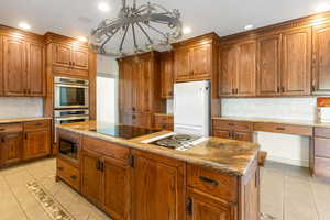 Kitchen with a center island, backsplash, dark stone counters, light tile patterned flooring, and appliances with stainless steel finishes