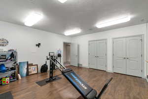 Exercise area featuring a textured ceiling and dark hardwood / wood-style floors