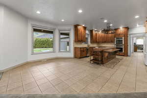 Kitchen featuring recessed lighting, stainless steel appliances, light tile patterned floors, tasteful backsplash, and a center island