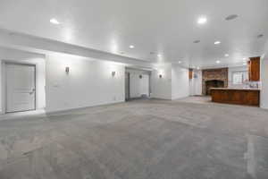 Unfurnished living room with a brick fireplace, recessed lighting, light carpet, and baseboards