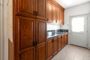 Mudroom featuring light tile patterned flooring and dark stone counters with custom cabinents