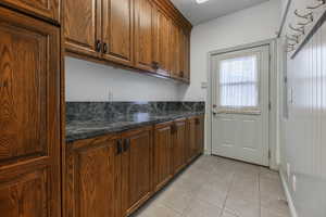 Kitchen with dark stone countertops and light tile patterned floors