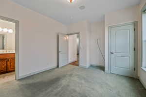 Unfurnished bedroom featuring light colored carpet, connected bathroom, a sink, and baseboards