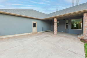 Back of house with stucco siding, a patio area, and a shingled roof