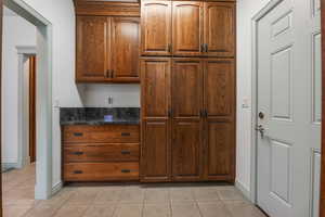 Kitchen with baseboards, light tile patterned floors, and dark stone counters