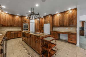 Kitchen featuring recessed lighting, stainless steel appliances, light tile patterned flooring, built in study area, and a kitchen island