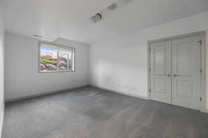 Unfurnished bedroom with carpet flooring, baseboards, and visible vents