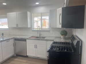 Kitchen featuring white cabinetry, sink, stainless steel appliances, and light hardwood / wood-style floors