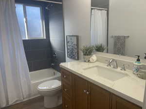 Full bathroom featuring toilet, shower / tub combo with curtain, vanity, and hardwood / wood-style flooring