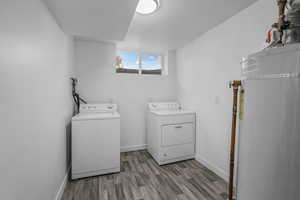 Washroom with water heater, separate washer and dryer, and light wood-type flooring