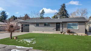 View of front of property with a garage and a front lawn