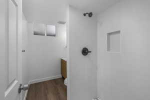 Bathroom featuring hardwood / wood-style floors, toilet, and tiled shower