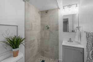 Bathroom with a tile shower, vanity, and toilet