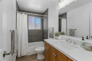 Full bathroom featuring vanity, wood-type flooring, toilet, and shower / bath combo