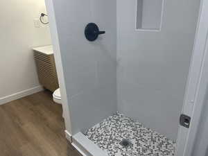 Bathroom featuring tiled shower, toilet, and hardwood / wood-style flooring