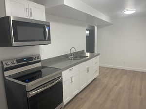 Kitchen featuring white cabinetry, sink, hardwood / wood-style flooring, and appliances with stainless steel finishes