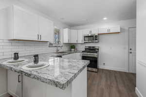 Kitchen featuring stainless steel appliances, sink, white cabinets, and kitchen peninsula