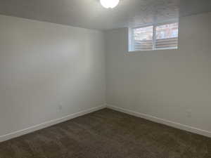 Spare room featuring a textured ceiling and dark colored carpet