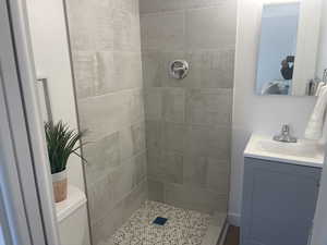 Bathroom featuring toilet, a tile shower, and vanity