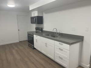 Kitchen featuring white cabinets, appliances with stainless steel finishes, dark hardwood / wood-style flooring, and sink