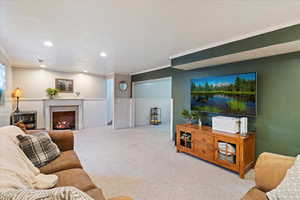 Carpeted living room with a textured ceiling, ornamental molding, and a fireplace