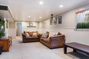 Living room with light colored carpet, ornamental molding, and a textured ceiling