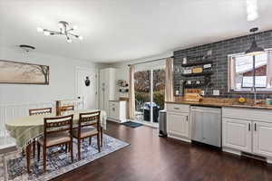 Kitchen with stainless steel dishwasher, decorative light fixtures, a healthy amount of sunlight, and white cabinetry