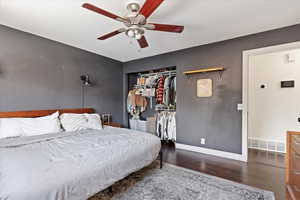 Bedroom featuring dark hardwood / wood-style floors, ceiling fan, and a closet