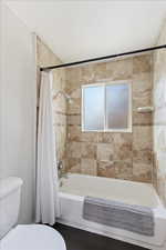 Bathroom featuring tile patterned flooring, toilet, and shower / bath combo with shower curtain