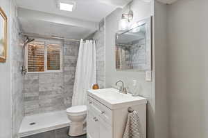 Bathroom featuring tile patterned flooring, vanity, curtained shower, and toilet