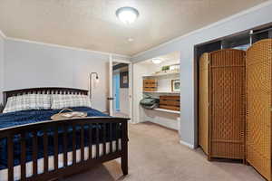 Bedroom featuring carpet flooring, a textured ceiling, and ornamental molding