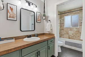 Full bathroom with tile patterned flooring, toilet, vanity, and tiled shower / bath