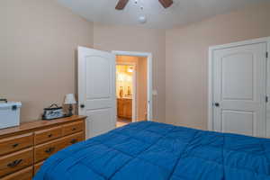 Bedroom with a textured ceiling, ensuite bath, and ceiling fan