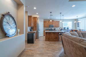 Kitchen featuring hanging light fixtures, stainless steel appliances, an inviting chandelier, light hardwood / wood-style flooring, and a kitchen bar