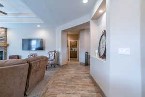 Living room featuring a stone fireplace, ceiling fan, light hardwood / wood-style floors, and a textured ceiling