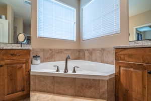 Bathroom featuring tile patterned floors, tiled bath, and vanity