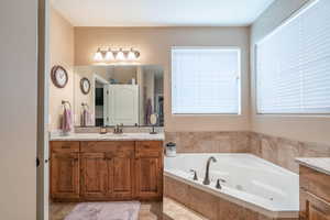 Bathroom with vanity, a relaxing tiled tub, and plenty of natural light