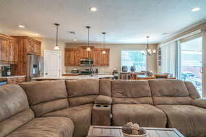 Living room featuring a notable chandelier, sink, a textured ceiling, and a wealth of natural light