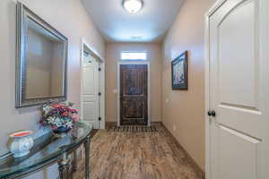 Doorway to outside featuring a textured ceiling and dark wood-type flooring