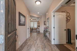 Hall with a textured ceiling and light hardwood / wood-style floors